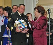 Ольга Федоровна Ботушанская вручает капитану второго ранга Аркадию Степаненко символический пакет книг