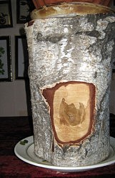 В «окошке» на березовом пеньке — коричневое пятно, давно проявилось само. Я о нем писала еще в 2015 году в статье «Музей вышивки Галины Манцоровой». Люди-тени в свободных одеждах за столом. Не нарисованы, не вышиты. Недавно в «столе» появилась трещина. Сама по себе. Не отражение ли это реальности?.. 